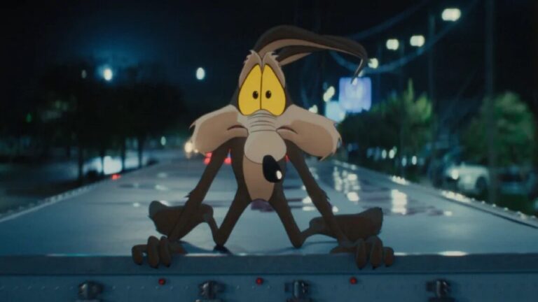 Review: Coyote vs. Acme is an unabashed love letter to Looney Tunes cartoon Wile E. Coyote on hood of car looking in window with a panicked wide-eyed expression